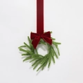Dettaglio della ghirlanda natalizia verde artificiale con un lungo fiocco in velluto rosso - Diametro Esterno 30cm / Fiocco di Velluto Rosso Vino