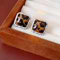 Detailed macro view of square leopard print stud earrings in a premium jewelry box - Coffee Square