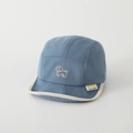 Dettaglio del cappellino bimbo con ricamo a cane ed etichetta laterale del marchio - 50cm (1-3 anni) / Blu