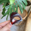 Macro view of a tortoiseshell acetate hair claw clip held in hand with lifestyle backdrop - Mini Cat Ear / Matte Red Brown