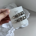 Nahaufnahme grauer Kristall-Haarklammern aus Metall auf weißer Kartonverpackung - Wassertropfen-Stil