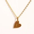 Détail macro du pendentif cœur doré avec gravure de la lettre E sur chaîne fine - Lettre E
