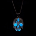 Makroansicht einer blau leuchtenden Totenkopf-Halskette mit Blitzsymbol und Leuchteffekt - Blau