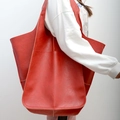 Close-up of bright red oversized faux leather tote bag showing soft texture on a model - Red