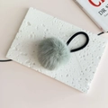 Close-up of a soft mint green pompom hair tie on a decorative stone with high-elastic band - Fruit Green