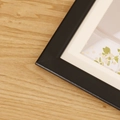 Modern black wooden picture frame with off-white matting featuring a floral art print - Black