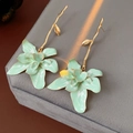 Details von Vintage Gold Zweig Ohrringen mit hellgrünen Emaille Blüten auf grauem Stoff - Grün