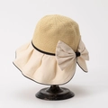 Dettaglio di un cappello di paglia beige con grande fiocco su supporto in metallo nero - M (56-58cm) / Bianco Sporco