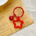 Detail of a red star flower acrylic keychain with a red bell and silver metal ring - Red