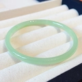 Round green jade gemstone bracelet displayed on a professional jewelry velvet stand - Extra Thin: Light Green Jade 60mm Diameter