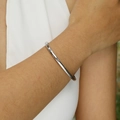 Brazalete minimalista de acero inoxidable pulido plateado en la muñeca de una mujer - Color Acero