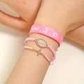 Detail of pink WWJD woven wristband with rhinestone cross and Virgin Mary charms - Three-Piece Set / Pink Portrait Style