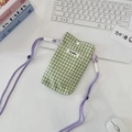 Detailed shot of a green checkered fabric phone pouch with a purple shoulder strap - Green Plaid