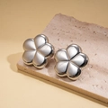 Close-up of silver metal flower earrings with a high-polish finish on a stone pedestal - Silver