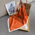 Detalle de un pañuelo de seda floral naranja y marrón anudado a un bolso de mano - 70x70cm / Rojo Anaranjado