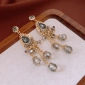 Detaillierte Nahaufnahme goldener Quastenohrringe mit dunkelgrauen Kristallen und Strass - Retro Quasten Stil / Gold