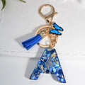 Royal blue resin letter A keychain with tassel and butterfly charm on white background - Letter A