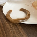 Close-up of brown marble resin cuff bracelet on a white ceramic tray with wood background - Coffee Marble