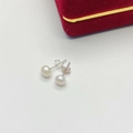 Macro detail of elegant round white pearl earrings with silver metal posts on leather - 5mm