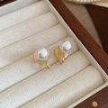 Close-up of elegant pearl clip-on earrings on a beige velvet jewelry box cushion - Ear Clip-Gold-White 8mm