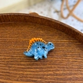 Vue macro de la pince à cheveux dinosaure en acétate bleu avec détails oranges - Mini Dinosaure Bleu