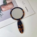 Portable round acetate hand mirror with tortoiseshell texture in a stylish daily setting - Leopard Print
