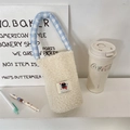 Detailed view of plush white water bottle carrier with blue checkered strap and cat patch - Off-white