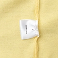 Detail view of the wash care label showing 100% viscose material and size S on yellow knit fabric - S / Yellow