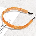 Detail shot of orange resin chain headband on a minimalist textured white background - Brown