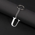 Silver stainless steel letter U keychain pendant on black leather textured surface - Letter U