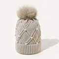Detail of beige knit beanie with large pompom, diamond pattern, and white pearl accents - Beige