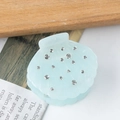Pinza para el pelo azul claro en forma de concha con pedrería sobre fondo de madera - Azul claro