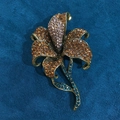 Dettaglio della spilla a giglio vintage con strass ambra e rosa su base in bronzo - Champagne