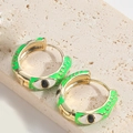 Gold hoop earrings with green enamel evil eye pattern on a beige stone surface - Green