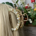 Lichtgouden haarklem met handgewikkelde groene stenen en witte parels op blond haar - Prehniet Gouden Haarklem