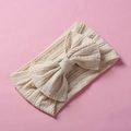 Detailed view of cream jacquard knitted baby headband with large bow on pink background - Dirty White