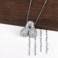 Macro della collana con ciondolo a lettera d'argento e zirconi su sfondo di legno - Lettera A