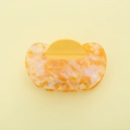 Detail view of the orange and white marble acetate hair claw clip with a glossy finish - Sycee / Ingot