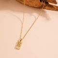 Vue détaillée du pendentif tarot vintage doré avec zircons sur une branche en bois - Roue de la Fortune (C119)