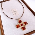 Dettaglio di un ciondolo a croce vintage con gemma ambrata e perla su cordoncino intrecciato - Marrone oro