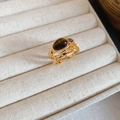 Macro-opname van een gouden dubbele ring met bruine tijgeroogsteen in een sieradendoos - Open Ring (Goud-Koffie)