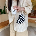 Close-up of a black and white checkerboard knit drawstring pouch held by a model - Black Check