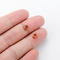 Handheld view of two mini gold stainless steel star charms with pink zircon inlay - Red Zirconia Star