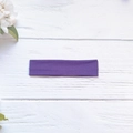 Detailed texture of high-elasticity purple yoga headband on rustic white wood background - Deep purple