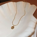 Detailed close-up of a gold necklace with a round cat-eye stone pendant in a white shell dish - Gold Bamboo Style Round Bead Necklace (HN4717)