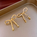 Detailed view of golden beaded bow earrings crafted from metallic cubes on a tray - Geometric Metal Woven Bow (43#)