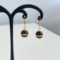 Gedetailleerde close-up van tijgeroog bolvormige oorbellen met gouden metalen ringen - Gouden Oorbellen (DEK590)