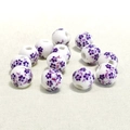 Vue macro de perles en céramique blanche de 10mm avec motifs floraux violets et trous - 10mm / Petite Fleur de Prunier Violette
