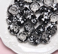 Hand-painted black and clear glass beads with white smiley faces on a ceramic tray - Clear Bead + Black Cream + e