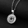Macro shot of silver letter G sunflower pendant with cubic zirconia on black leather - Silver Letter G